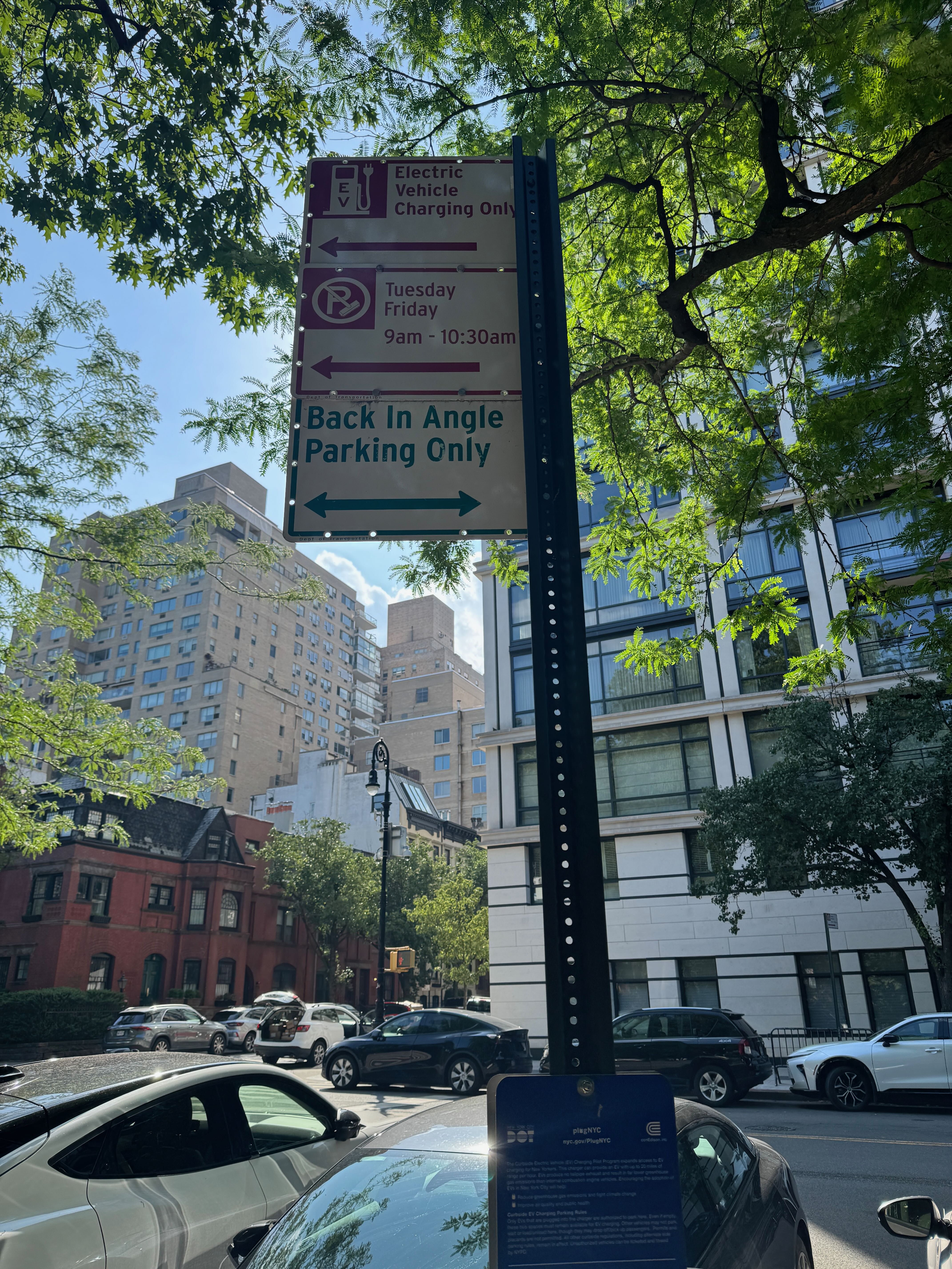 Street sign reserving two spots for electric vehicle charging only, with alternate side parking rules still in effect